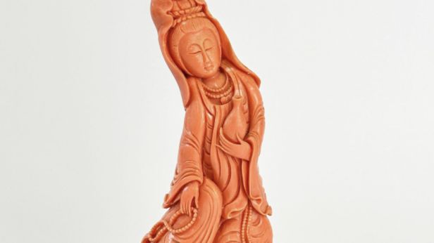 Statuette de Guanyin en corail rouge-orangé, le vase à eau lustrale dans la main gauche, le mala dans la main droite. Chine, XXe siècle.