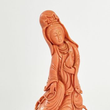 Statuette de Guanyin en corail rouge-orangé, le vase à eau lustrale dans la main gauche, le mala dans la main droite. Chine, XXe siècle.