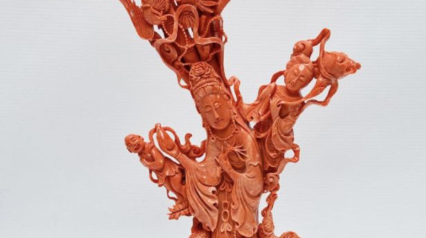 CHINE, XXème siècle Statuette en corail rose orangé, la déesse Guanyin tenant le vase à eau lustrale