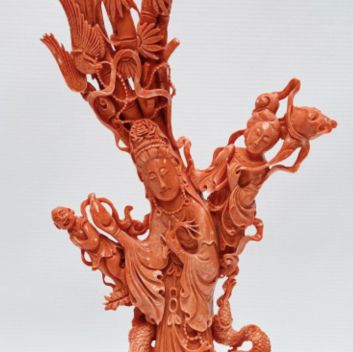 CHINE, XXème siècle Statuette en corail rose orangé, la déesse Guanyin tenant le vase à eau lustrale