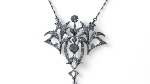 Collier pendentif en or gris 18k (750e) et platine, stylisant des volutes végétales, ornée de diamants taille ancienne