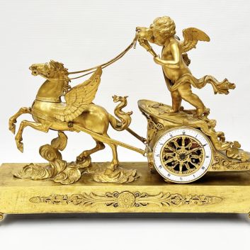 Pendule en bronze doré figurant Cupidon conduisant dans les nuées un char