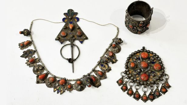 Ensemble de quatre bijoux kabyles en argent (800), émail et cabochons de corail comprenant une fibule