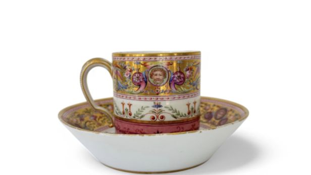 SÈVRES Rare gobelet litron et une soucoupe de 2e grandeur en porcelaine dure, à décor polychrome néoclassique d’une frise de grotesques sur fond or